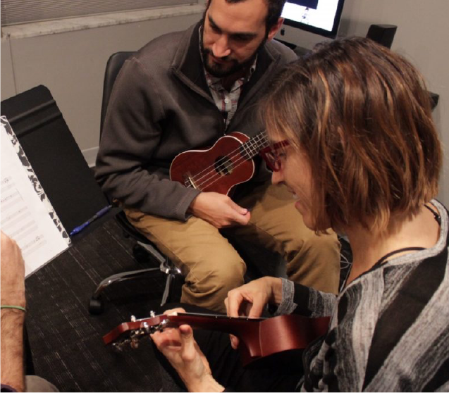 Music instructor teaching students how to play the ukulele during a private lesson.